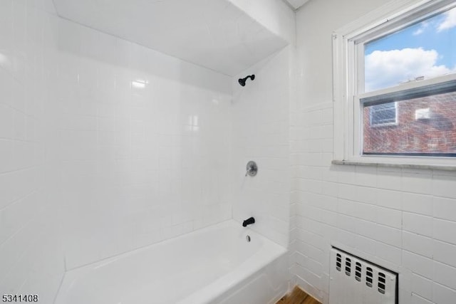 full bath with radiator heating unit, shower / bath combination, and tile walls