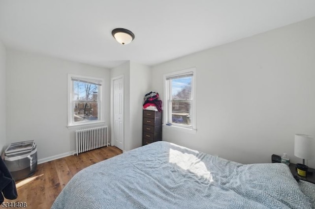 bedroom featuring radiator, baseboards, and wood finished floors