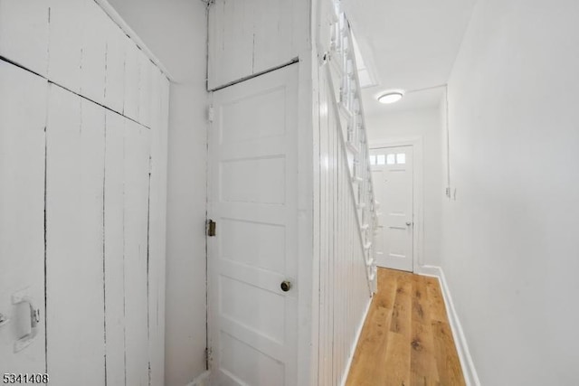 corridor featuring baseboards and light wood finished floors