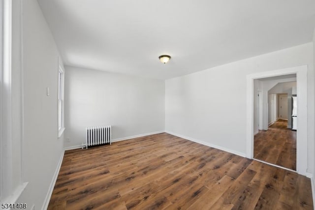 empty room featuring radiator heating unit, baseboards, and wood finished floors