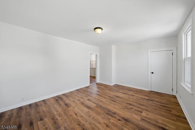 spare room featuring a wealth of natural light, baseboards, and wood finished floors