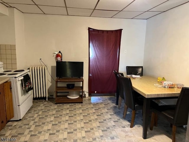 dining room featuring radiator heating unit and a drop ceiling