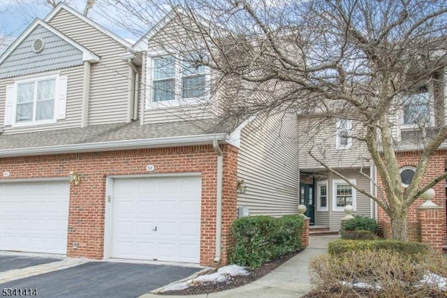 multi unit property with brick siding, a shingled roof, aphalt driveway, and a garage