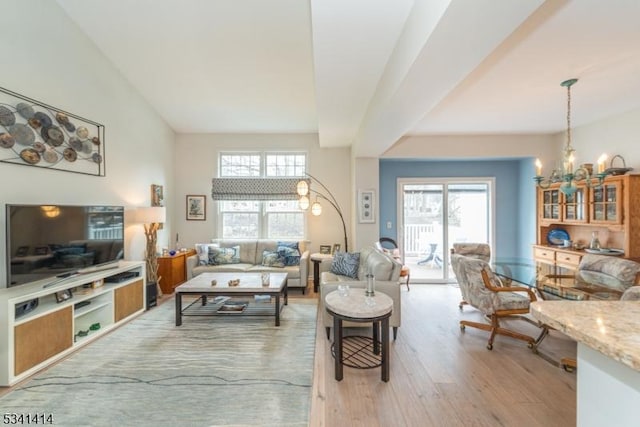 living area with light wood-type flooring, a healthy amount of sunlight, and an inviting chandelier