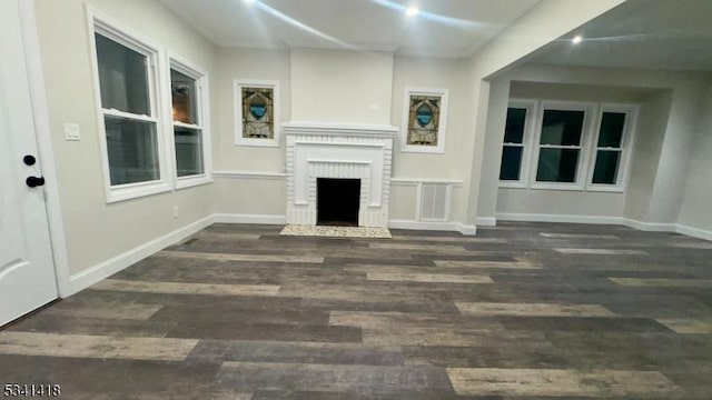 unfurnished living room with a fireplace, baseboards, and wood finished floors