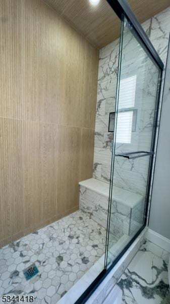 full bath featuring marble finish floor, a marble finish shower, and baseboards