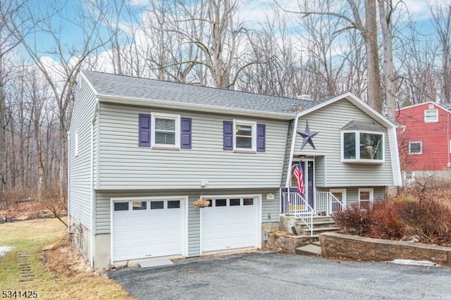 bi-level home with a garage, roof with shingles, a chimney, and aphalt driveway