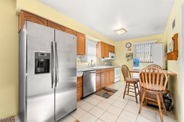 kitchen featuring light tile patterned floors, stainless steel appliances, light countertops, visible vents, and a sink