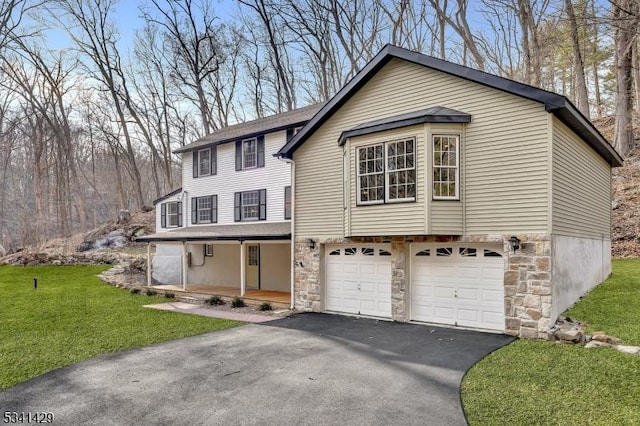 view of front of house with covered porch, an attached garage, stone siding, driveway, and a front lawn