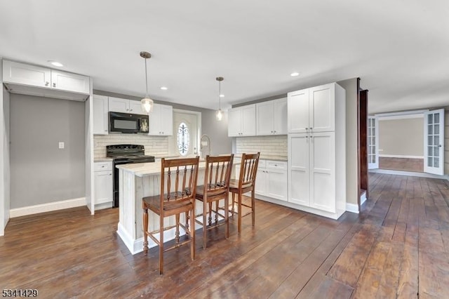 kitchen featuring dark wood-style floors, black appliances, light countertops, and white cabinets