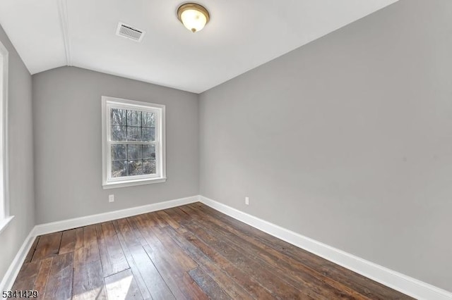 unfurnished room with vaulted ceiling, dark wood-type flooring, visible vents, and baseboards