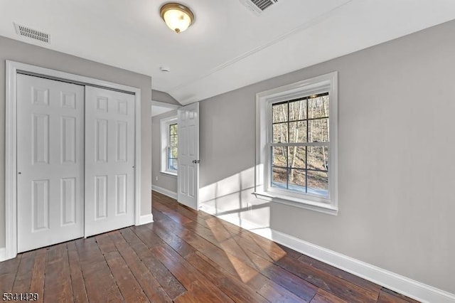 unfurnished bedroom with hardwood / wood-style flooring, visible vents, and baseboards