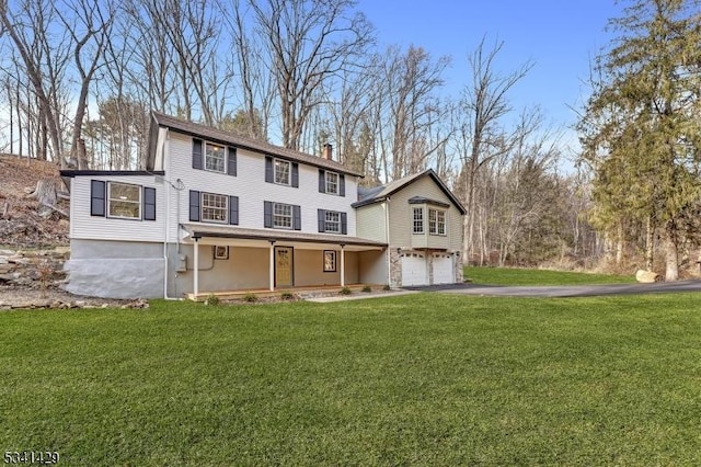 view of front of home featuring driveway, an attached garage, a chimney, and a front lawn