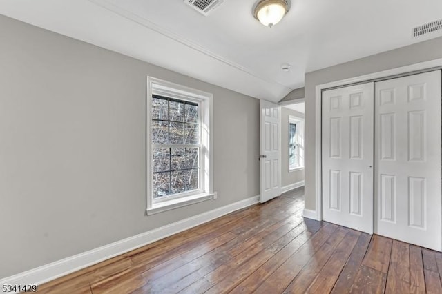 unfurnished bedroom featuring dark wood-style floors, baseboards, visible vents, and a closet