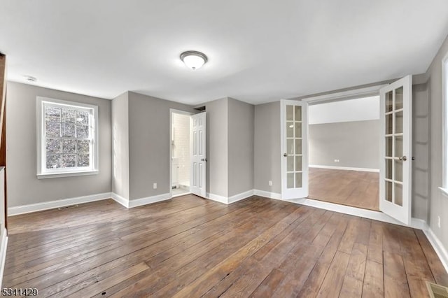 unfurnished room with visible vents, baseboards, hardwood / wood-style floors, and french doors