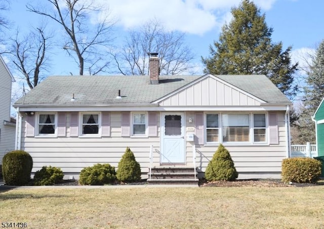 view of front of property featuring entry steps, a chimney, and a front yard