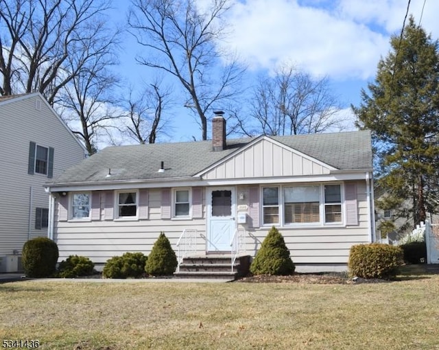 view of front of house featuring a shingled roof, a chimney, central air condition unit, board and batten siding, and a front yard