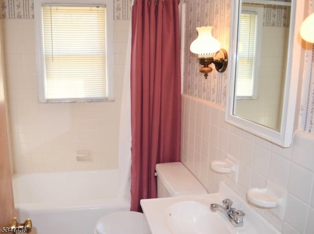 bathroom featuring a sink, tile walls, toilet, and wallpapered walls