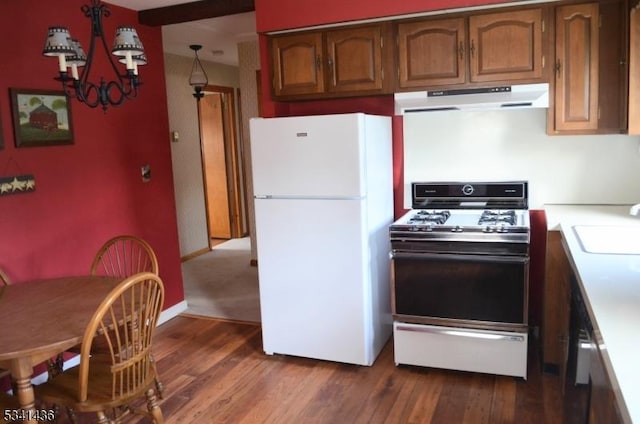 kitchen featuring a sink, freestanding refrigerator, range hood, dark wood-style floors, and gas range oven