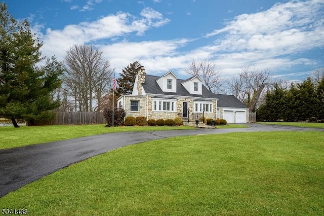 cape cod home featuring a garage, stone siding, aphalt driveway, fence, and a front lawn