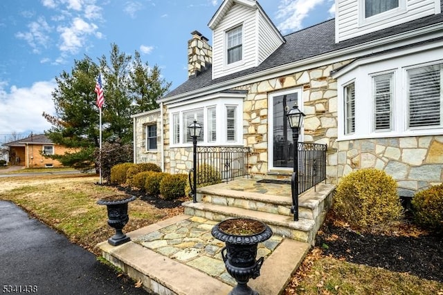 property entrance featuring stone siding and a chimney