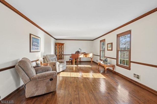 living room with ornamental molding, visible vents, baseboards, and wood finished floors