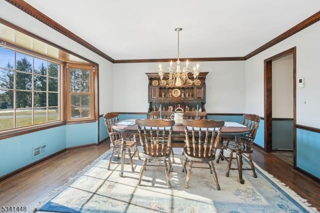 dining room with crown molding, a notable chandelier, and wood finished floors