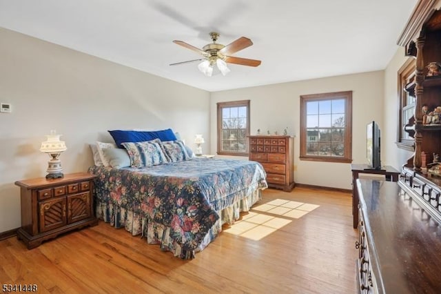 bedroom with a ceiling fan, light wood-style flooring, and baseboards