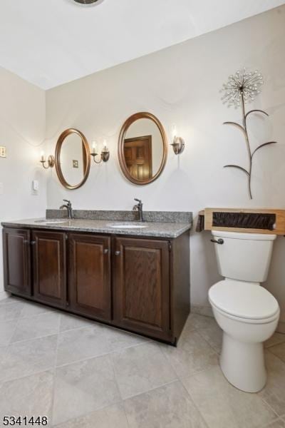 bathroom featuring double vanity, a sink, toilet, and tile patterned floors