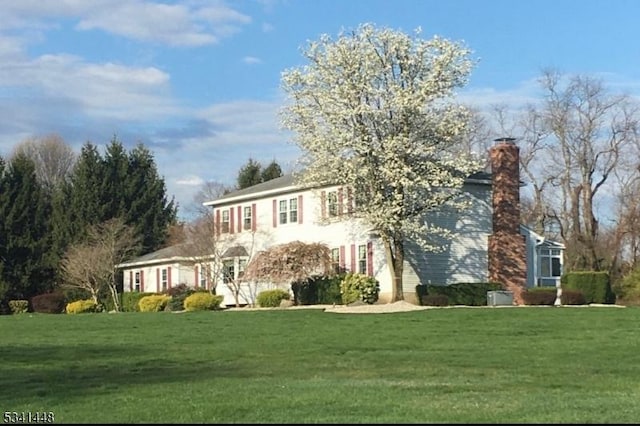 colonial home with a chimney and a front yard