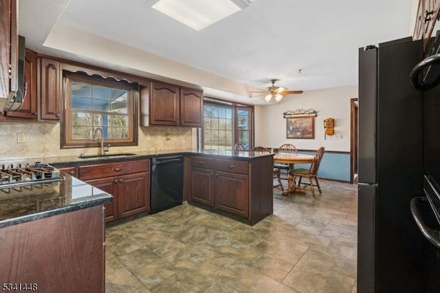 kitchen featuring decorative backsplash, a sink, a peninsula, and black appliances