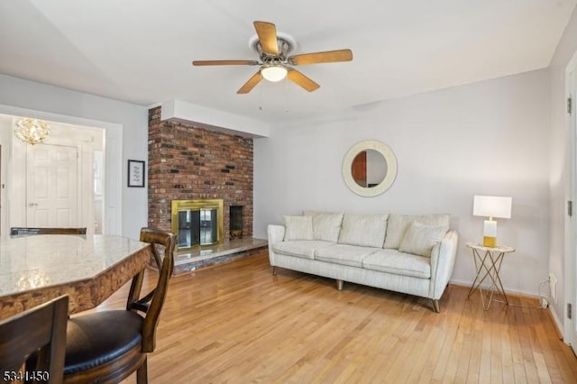 living room featuring a fireplace, light wood-style floors, baseboards, and ceiling fan