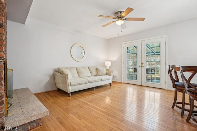 living room with light wood-style flooring, french doors, baseboards, and a ceiling fan