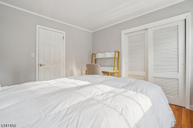 bedroom with a closet, wood finished floors, and ornamental molding