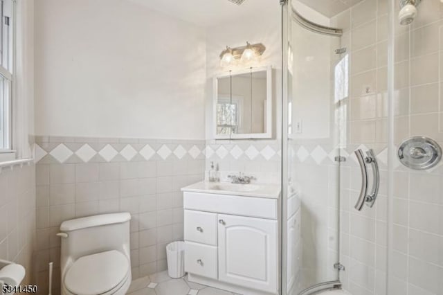 bathroom featuring vanity, a shower stall, toilet, and tile walls