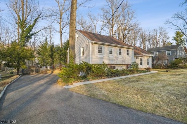 view of front of house with aphalt driveway, a front lawn, and a chimney