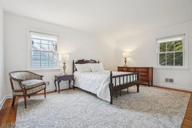 bedroom with wood finished floors, visible vents, and baseboards