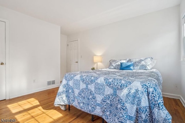 bedroom with visible vents, baseboards, and wood finished floors