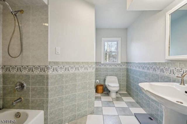 full bathroom featuring a wainscoted wall, toilet, shower / bath combination, tile walls, and a sink