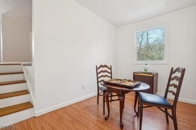 dining room featuring baseboards, stairs, and light wood finished floors