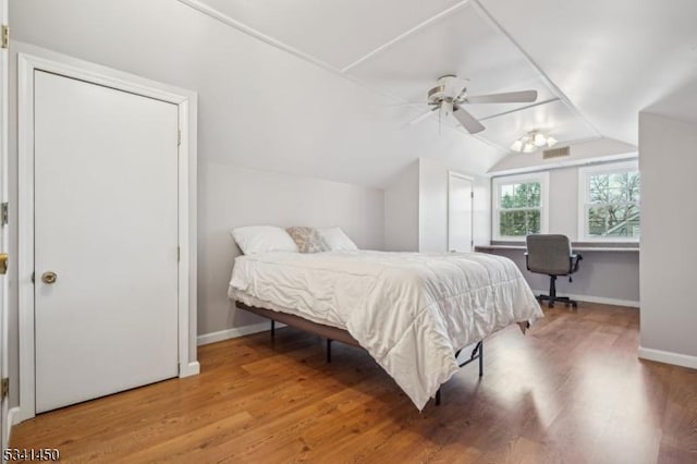 bedroom with visible vents, baseboards, lofted ceiling, and wood finished floors