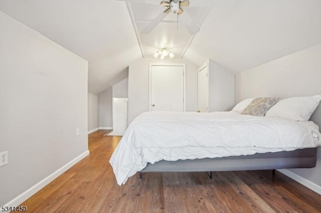 bedroom featuring lofted ceiling, wood finished floors, and baseboards