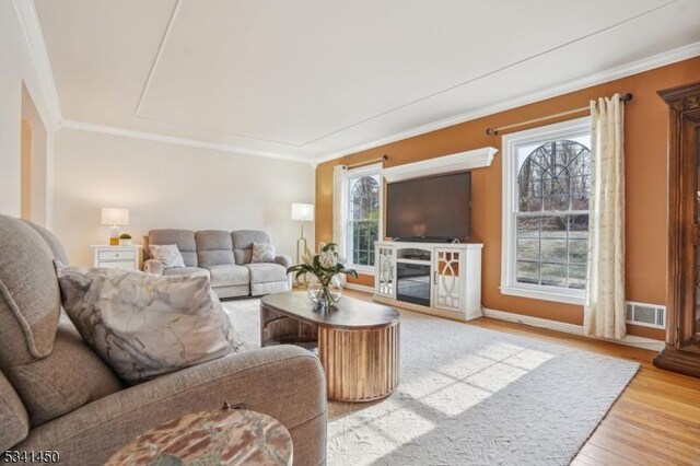 living room with visible vents, a fireplace, wood finished floors, and crown molding