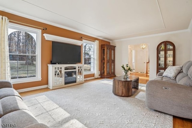 living area with ornamental molding, baseboards, and wood finished floors