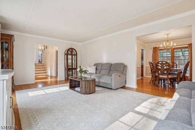 living room featuring ornamental molding, stairs, an inviting chandelier, and wood finished floors