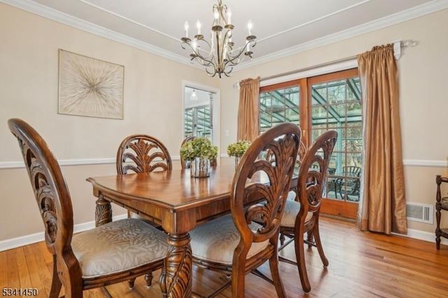 dining space with light wood-style flooring, a notable chandelier, baseboards, and ornamental molding