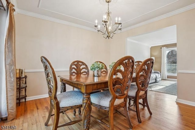 dining area featuring a notable chandelier, light wood-style flooring, baseboards, and ornamental molding