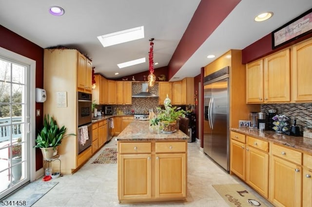 kitchen featuring lofted ceiling with skylight, light stone counters, a center island, stainless steel built in fridge, and wall chimney range hood