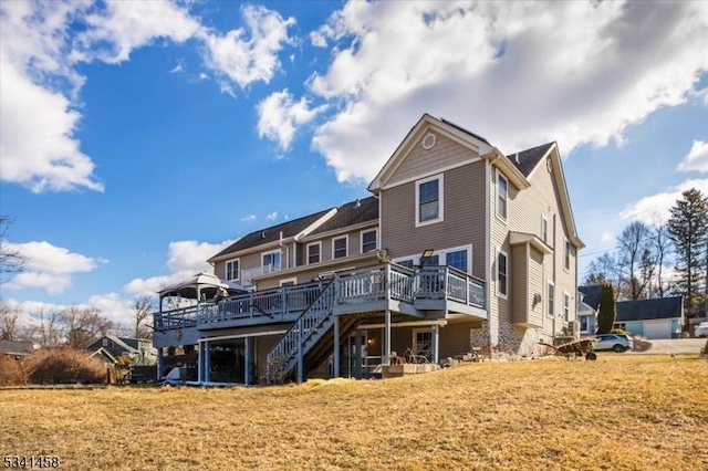 rear view of house featuring a yard, stairway, and a wooden deck