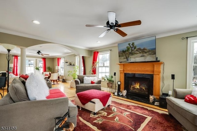 living room featuring arched walkways, a ceiling fan, crown molding, ornate columns, and recessed lighting